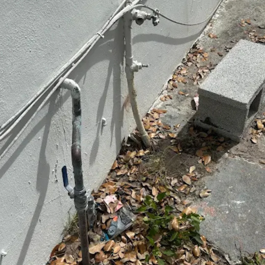 Corroded outdoor copper water line attached to exterior wall, showing damaged plumbing that needs repair or replacement.