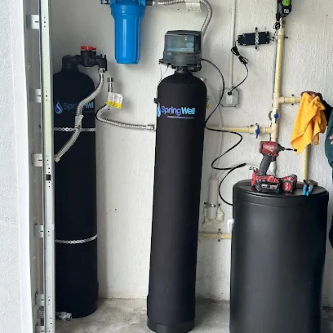 SpringWell whole-house water filtration and water softener system installed in a utility room with connected pipes, tanks, and filtration components.