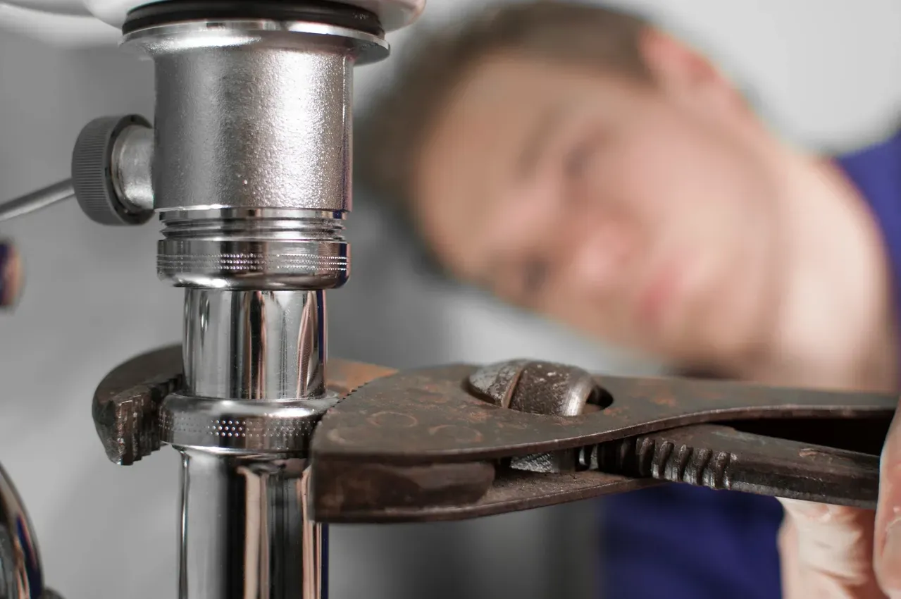 Plumber using a wrench to tighten pipes for plumbing repairs and installations.